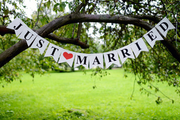 Beautiful wedding inscription 'just married' on the nature. Close-up beauty of colored placard. Bridal accessories. Female and male decoration for couple. Details for marriage