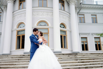 Wedding couple on the nature is hugging each other. Beautiful model girl in white dress. Man in suit. Beauty bride with groom. Female and male portrait. Woman with lace veil. Lady and guy outdoors