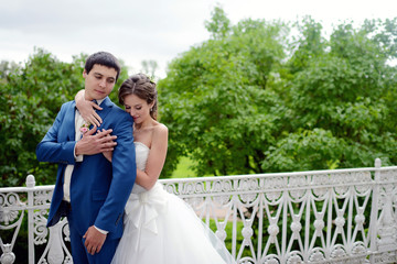 Wedding couple on the nature is hugging each other. Beautiful model girl in white dress. Man in suit. Beauty bride with groom. Female and male portrait. Woman with lace veil. Lady and guy outdoors