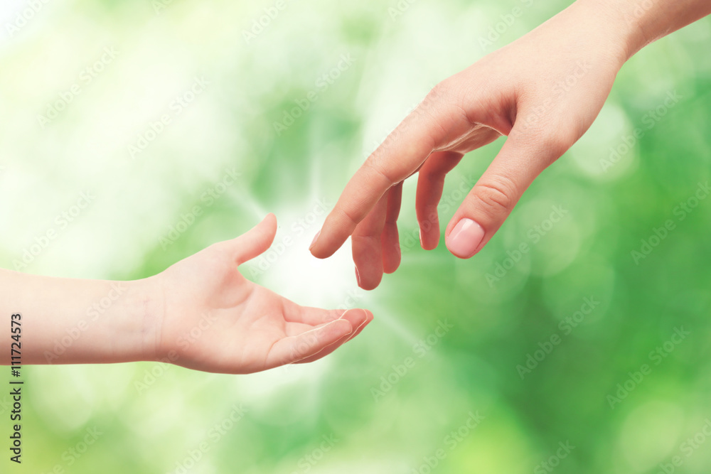 Wall mural Child and mother hands on green nature background. Concept of taking care, protection, helping and assistance