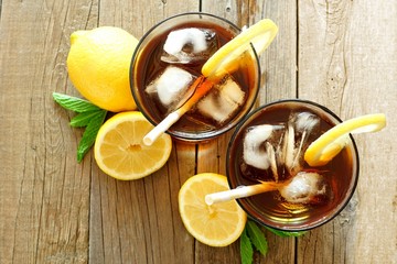 Two glasses of iced tea with lemon, overhead view on a rustic wooden background