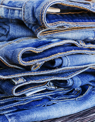 stack of jeans lying on a wooden table