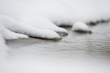 Fototapeta na wymiar A snow covered edge of a small stream.