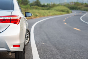Back side of new silver car parking on the asphalt road