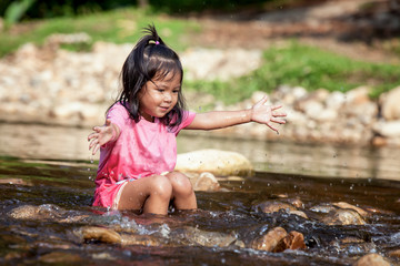 Child little girl having fun to play in waterfall