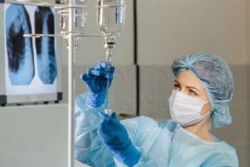 Female doctor adjusting infusion bottle in hospital