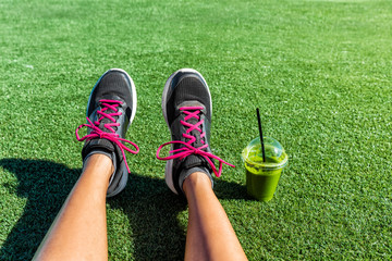 Healthy lifestyle runner girl running shoes selfie with green smoothie. Fitness woman drinking...
