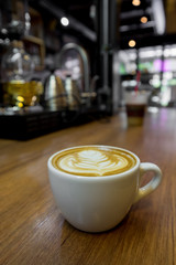 A cup of latte art coffee. Cappuccino coffee on wooden table wit