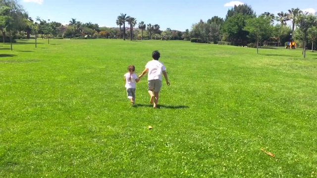 Brother and sister playing together at the park in a summer sunny day. Brother and sister concept.