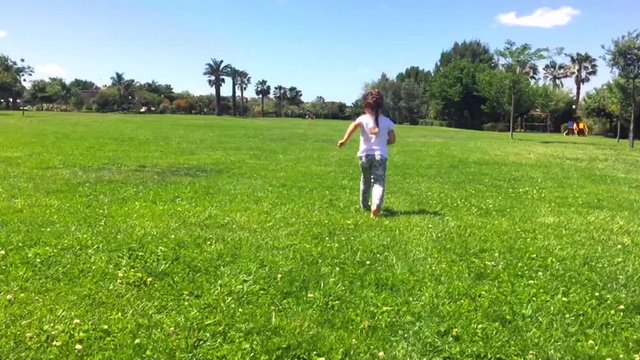 Young little girl run at the park in a summer sunny day. 