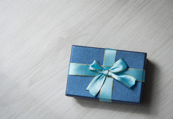 Blue gift box on gray wooden texture background with copyspace f