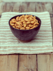 salty cashew nuts in black ceramic bowl on wood table