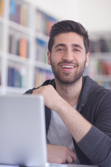 student in school library using laptop for research