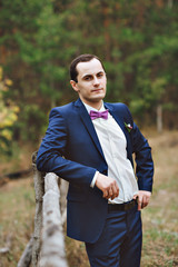 the groom in a blue suit and bow tie posing in the photo