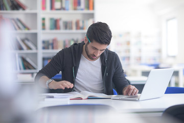 student in school library using laptop for research