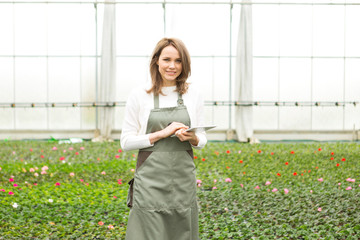 Young attractive woman working at the plants nursery using table