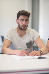 male student taking notes in classroom