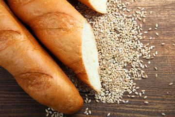 sliced baguette with wheat on wooden background