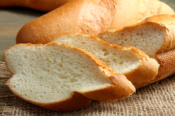 cut the baguette on sackcloth on wooden background