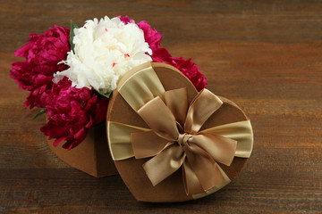 a bouquet of red and white peony on a wooden background near the boxes