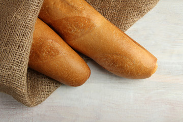 cut the baguette on sackcloth on wooden background