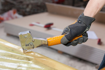 Building a wall for frame house. Worker installing vapor barrier film with staple gun