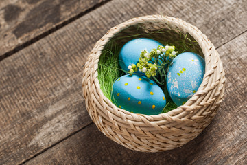 Obraz na płótnie Canvas Easter eggs in nest on color wooden background