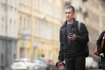 Young traveler with mobile phone in the street