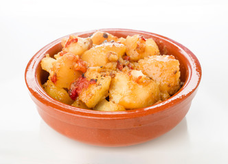 earthenware dish of stewed potatoes with peppers on white