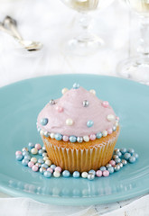 Cupcake decorated with cream and sugar pearls on plate