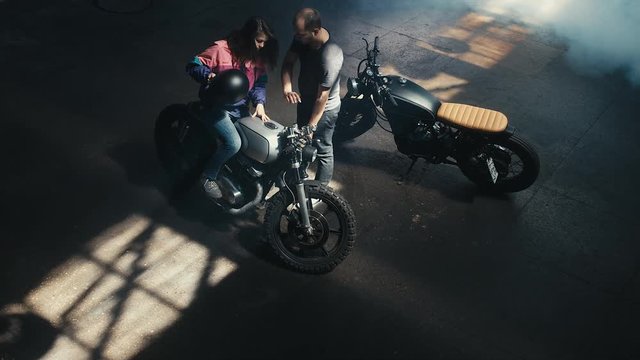 Wide overhead shot of young Caucasian male biker teaching his girlfriend to ride a motorcycle. 60 FPS slow motion Blackmagic URSA Mini RAW graded footage