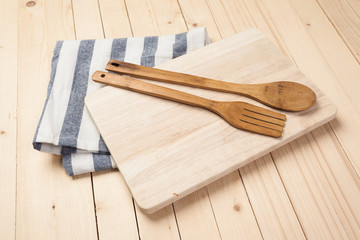 Wooden spoons and other cooking tools with blue napkins on the kitchen table.