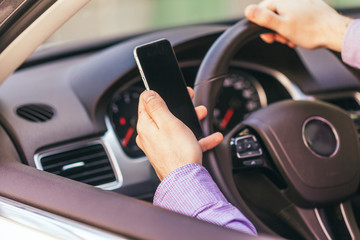  close up of young man hand with smartphone driving car