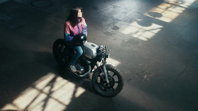 Wide overhead shot of young Caucasian male biker having a chat with a girl sitting on a motorcycle. 60 FPS slow motion Blackmagic URSA Mini RAW graded footage