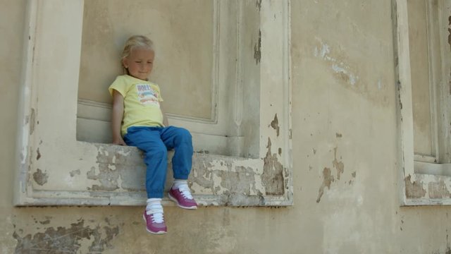 Piccola bambina bionda seduta su un muro a Roma, Italia, Europa