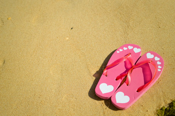 Fototapeta na wymiar Top view of flip flops left on sandy beach background