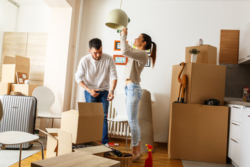 Young married couple cleaning and selecting furniture and accessories in their new home. Moving...