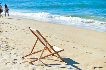 Fototapeta na wymiar Back view of deckchair on a beach, sunny blue ocean outdoors background 