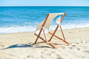 Fototapeta na wymiar Female hat and deckchair on the beach vacation, sunny background outdoors 