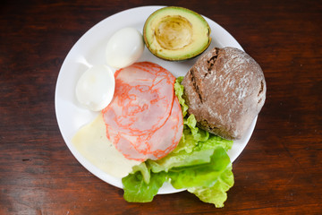 Avacado, bread, bacon and egg with salad in plate on table, closeup flat lay top view