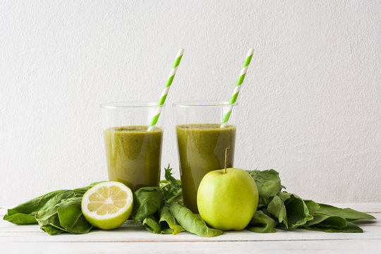 Healthy green detox with spinach, cucumber, lime and apples on white wooden table
