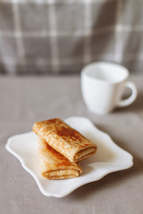 pancakes stuffed with tea and breakfast on a gray fabric background white dishes