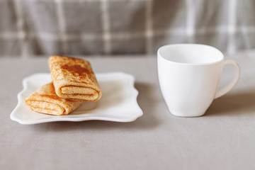 pancakes stuffed with tea and breakfast on a gray fabric background white dishes