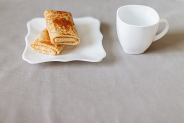 pancakes stuffed with tea and breakfast on a gray fabric background white dishes