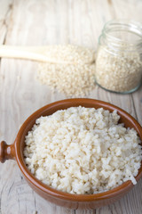 Cooked steamed rice in a blue bowl over wooden background