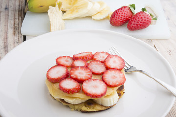 Stack of golden pancakes with strawberries, banana,