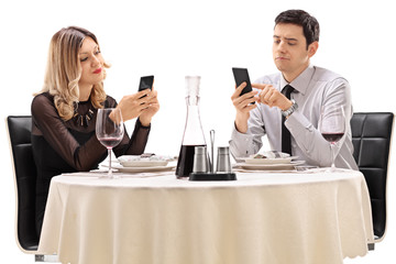 Couple on a date playing with their phones