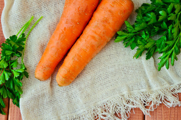 Two juicy carrots with parsley on a wooden table. Top view