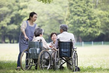 車椅子の夫婦とヘルパー
