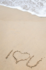 Top view of romantic sign hand drawing on the sandy beach